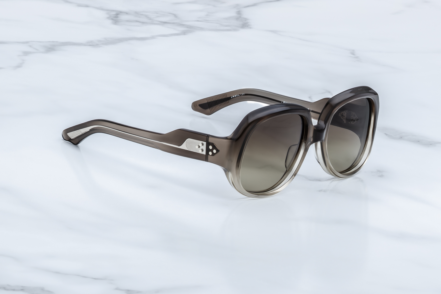 Side profile of Ocean Child Smoke Fade — double-laminated temples with clear outer and dark gray inner acetate, and exposed wire-core with art deco engraving