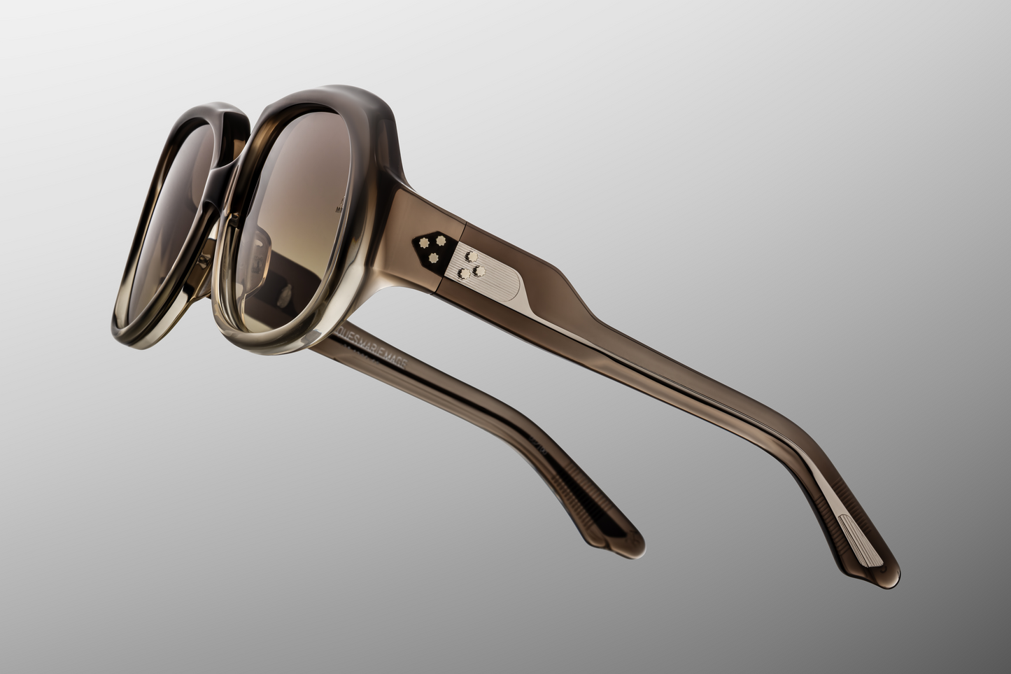 Side profile of Ocean Child Smoke Fade — double-laminated temples with clear outer and dark gray inner acetate, and exposed wire-core with art deco engraving