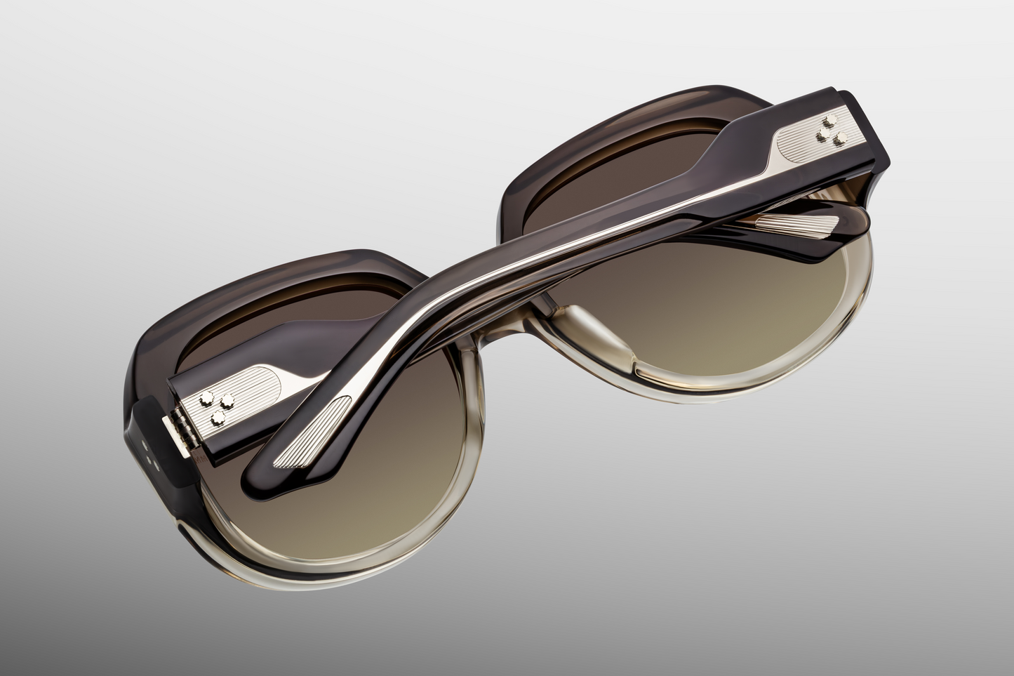 Interior of Ocean Child Smoke Fade — triple-gradient smoke Armorlite lenses framed by soft gray fade acetate, with JMM inner‑temple foil-stamped hallmarks