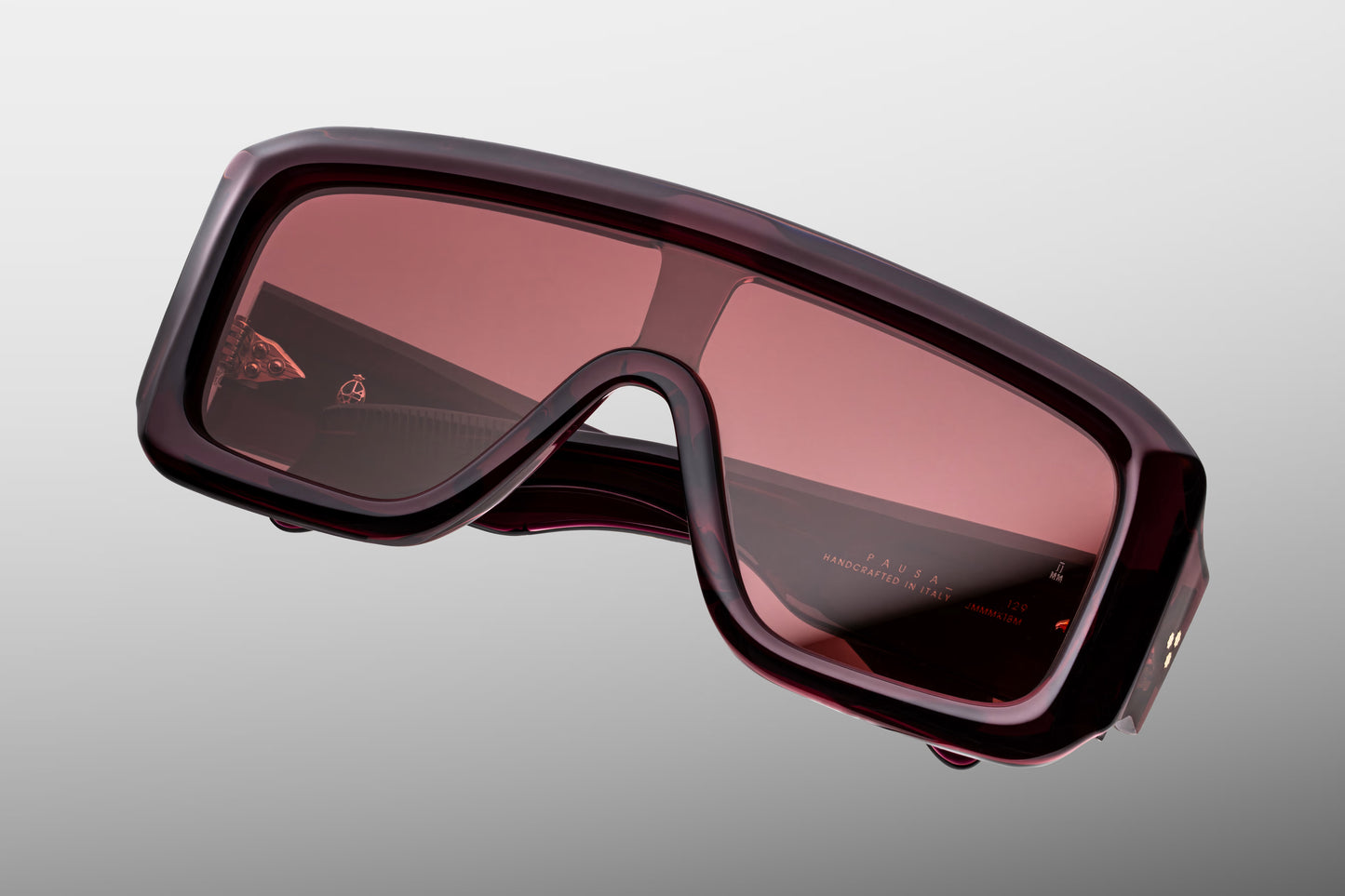 Close-up front detail of Jacques Marie Mage Pausa Amarena frame showing gold arrowhead pins, shield lens and polished red acetate
Macro front view of JMM Pausa Amarena sunglasses highlighting wraparound lens construction and luxury craftsmanship