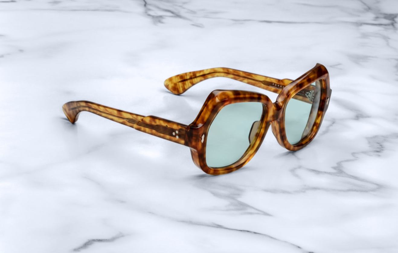 Side view of model wearing Perreti Camel: the tortoiseshell temple extends straight back from the front, showing its substantial 142 mm length. The hidden light‑gold wire‑core runs internally, while the tension‑secured 7‑barrel light‑gold hinge connects temple to front with refined precision. The temple is engraved with ‘PERRETI’ just behind the hinge, and curves gently inward at the ear tip for comfort.