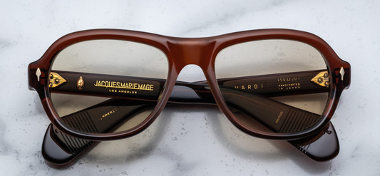 Jacques Marie Mage Richard sunglasses in Teak, featuring a modern aviator shape with a bold, sculpted silhouette. The frame is crafted from 10mm brown cured cellulose acetate, accented with dark gold arrowhead front pins and exposed wirecore details. The khaki glass CR39 lenses offer 100% UV protection and backside anti-reflective treatment