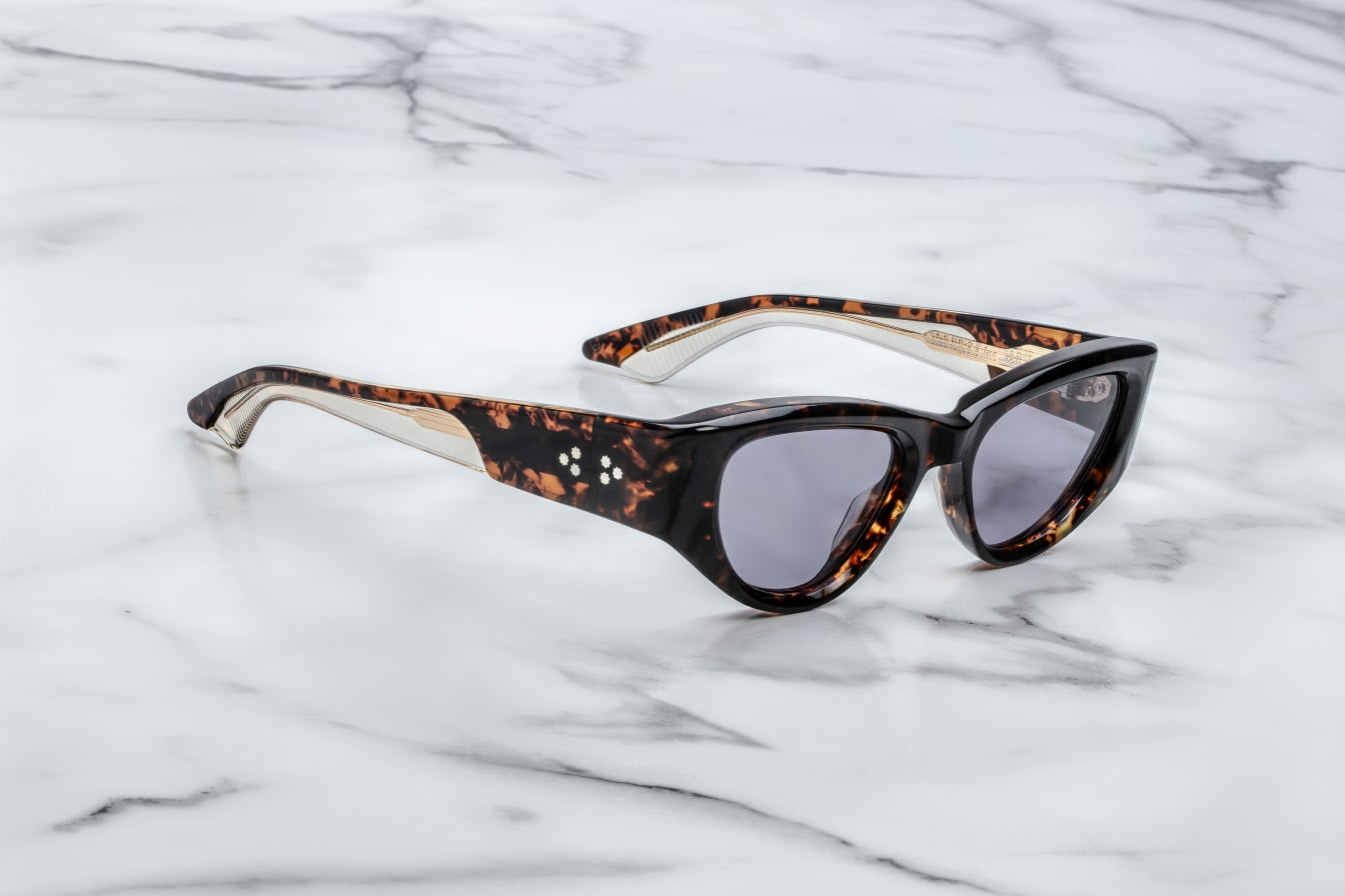 Side profile of Sey­mour Beau — double-laminated havana acetate temples showing exposed light-gold wirecore and light-gold custom 7-barrel hinge.
