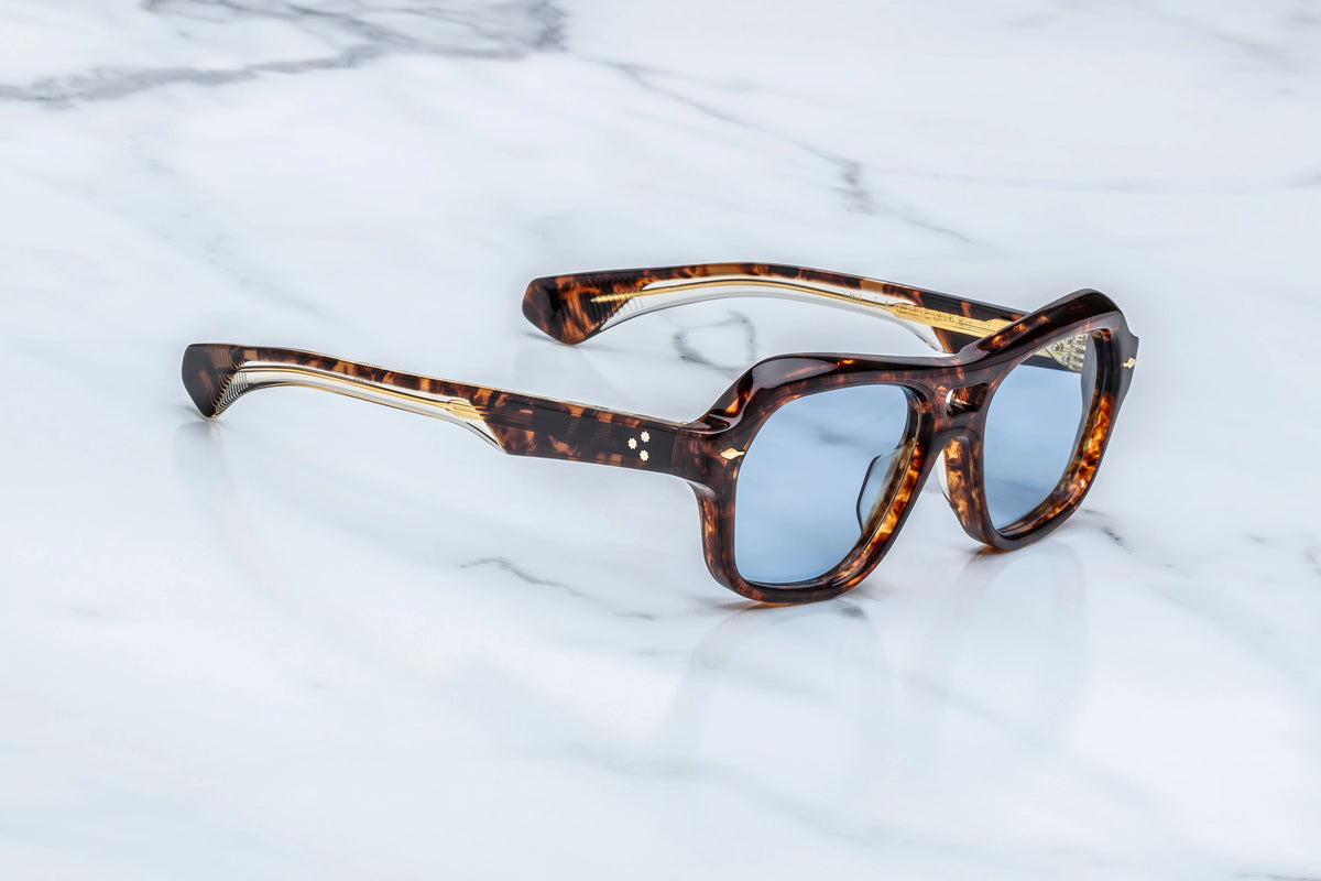• 
Three-quarter view of the Jacques Marie Mage Tamerlis sunglasses. This angle highlights the substantial 10mm block acetate profile, deep sculptural contouring across the bridge, and thick temple arms transitioning from the winged frame chassis.
