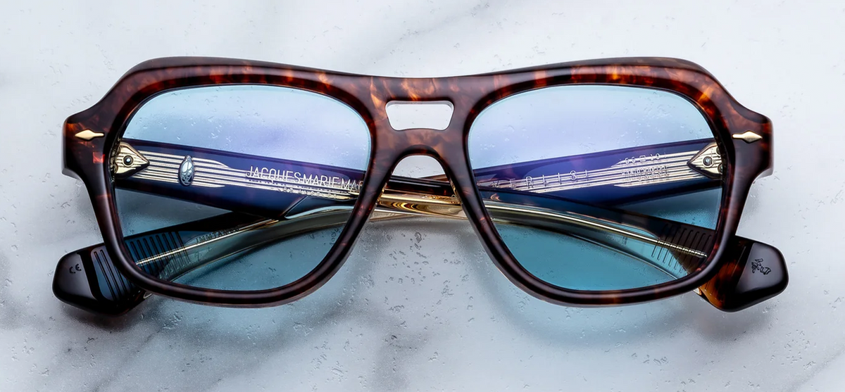 Front view of Jacques Marie Mage Tamerlis sunglasses. Displays a bold, late-1990s-inspired modified square frame with an aggressive, heavily beveled brow line, a structural double bridge, winged outer edges, and precious metal arrowhead pins.