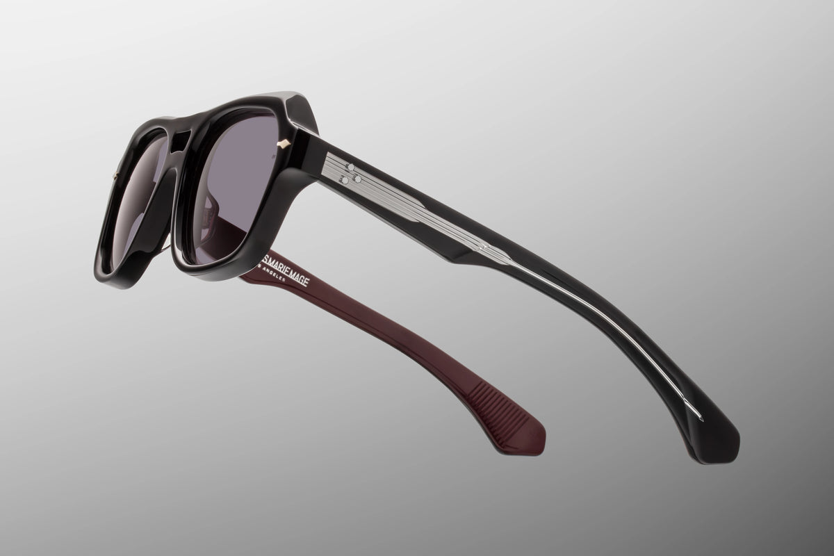 Macro shot of the temple arm on Jacques Marie Mage Tamerlis Bloodstone sunglasses. The crystal-clear exterior laminate layer acts as a window to an exposed silver palladium Lever wire core engraved with intricate Art Deco hairline filigree.