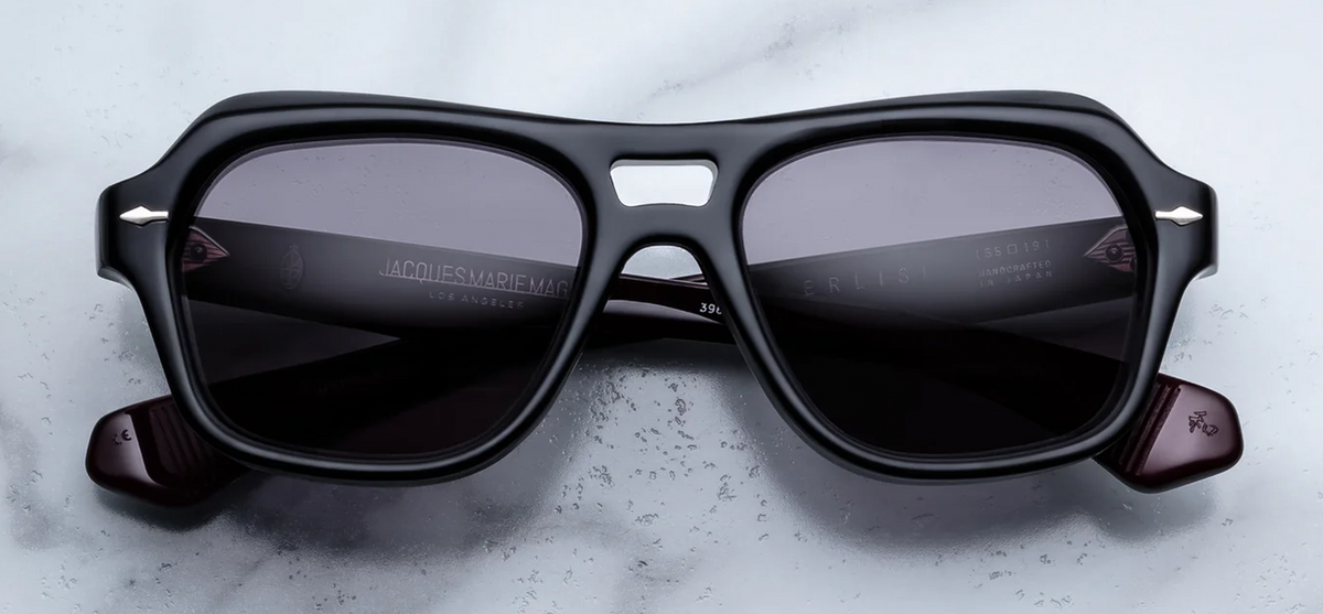 Front view of Jacques Marie Mage Tamerlis Bloodstone sunglasses. Displays an aggressive, late-1990s-inspired modified square frame in polished 10mm black block acetate, showcasing a distinct double bridge, heavily beveled winged brow line, deep jet-black lenses, and sterling silver arrowhead pins.