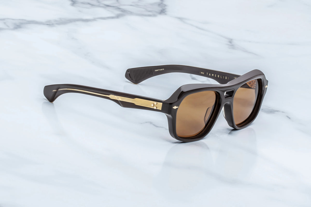 Three-quarter view of the Jacques Marie Mage Tamerlis Walnut sunglasses. This angle highlights the heavy 10mm block acetate profile and complex brow beveling, transitioning into dual-layered temples that reveal a dark gold filigree wire core through clear beige exterior acetate.