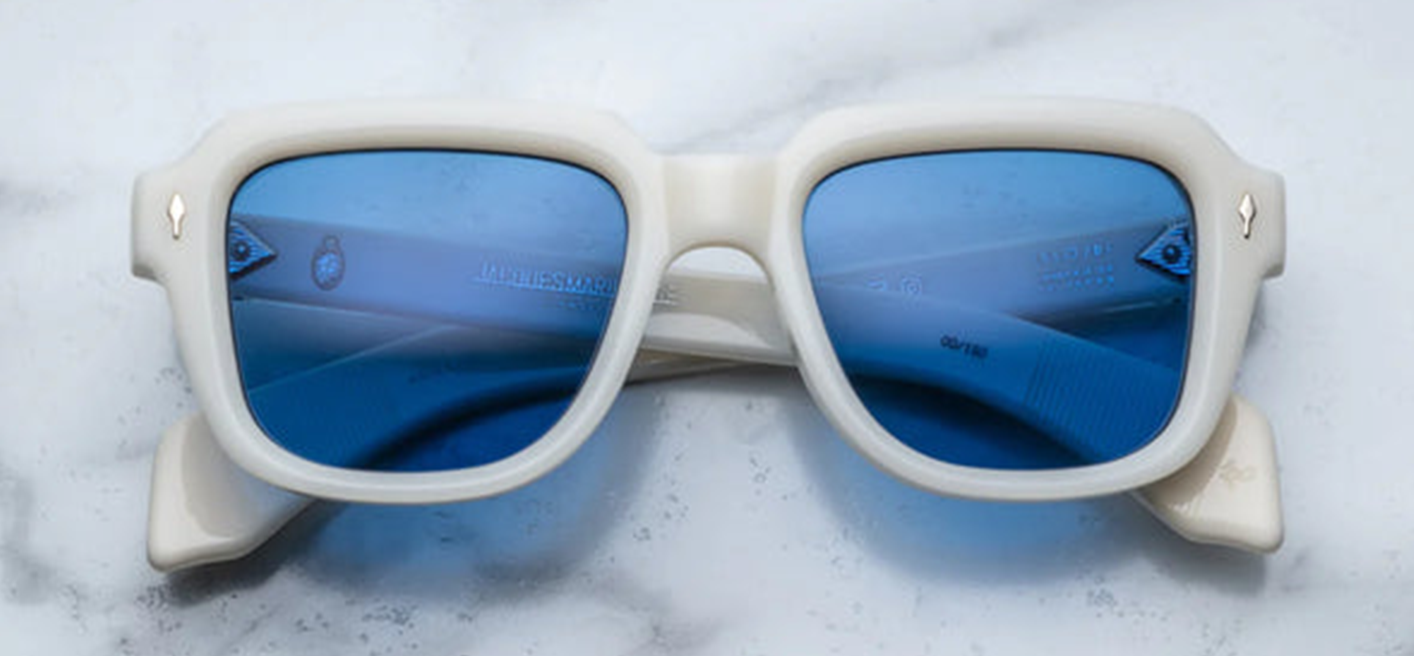 Jacques Marie Mage Taos in Mykonos sunglasses, bold, rectangular 10 mm white cured acetate frames evoking Mykonos’ architecture. They feature exposed silver wire‑core temples threaded with tribal-engraved detailing, vintage-style 4-base blue gradient CR39 lenses with backside anti‑reflective coating, and full UV protection. Inspired by Dennis Hopper’s eyewear in Easy Rider, this is a limited edition of 150 pieces at WINK Optometrists