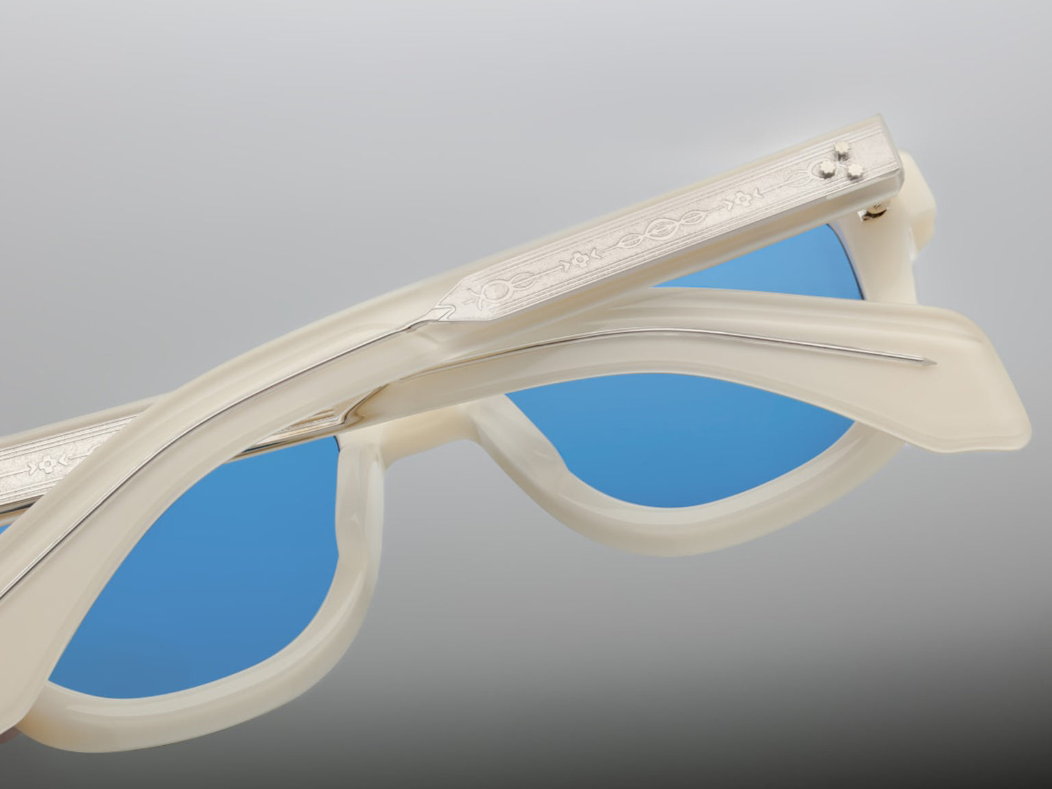Back view of Jacques Marie Mage Taos in Mykonos sunglasses, bold, rectangular 10 mm white cured acetate frames evoking Mykonos’ architecture. They feature exposed silver wire‑core temples threaded with tribal-engraved detailing, vintage-style 4-base blue gradient CR39 lenses with backside anti‑reflective coating, and full UV protection. Inspired by Dennis Hopper’s eyewear in Easy Rider, this is a limited edition of 150 pieces at WINK Optometrists
