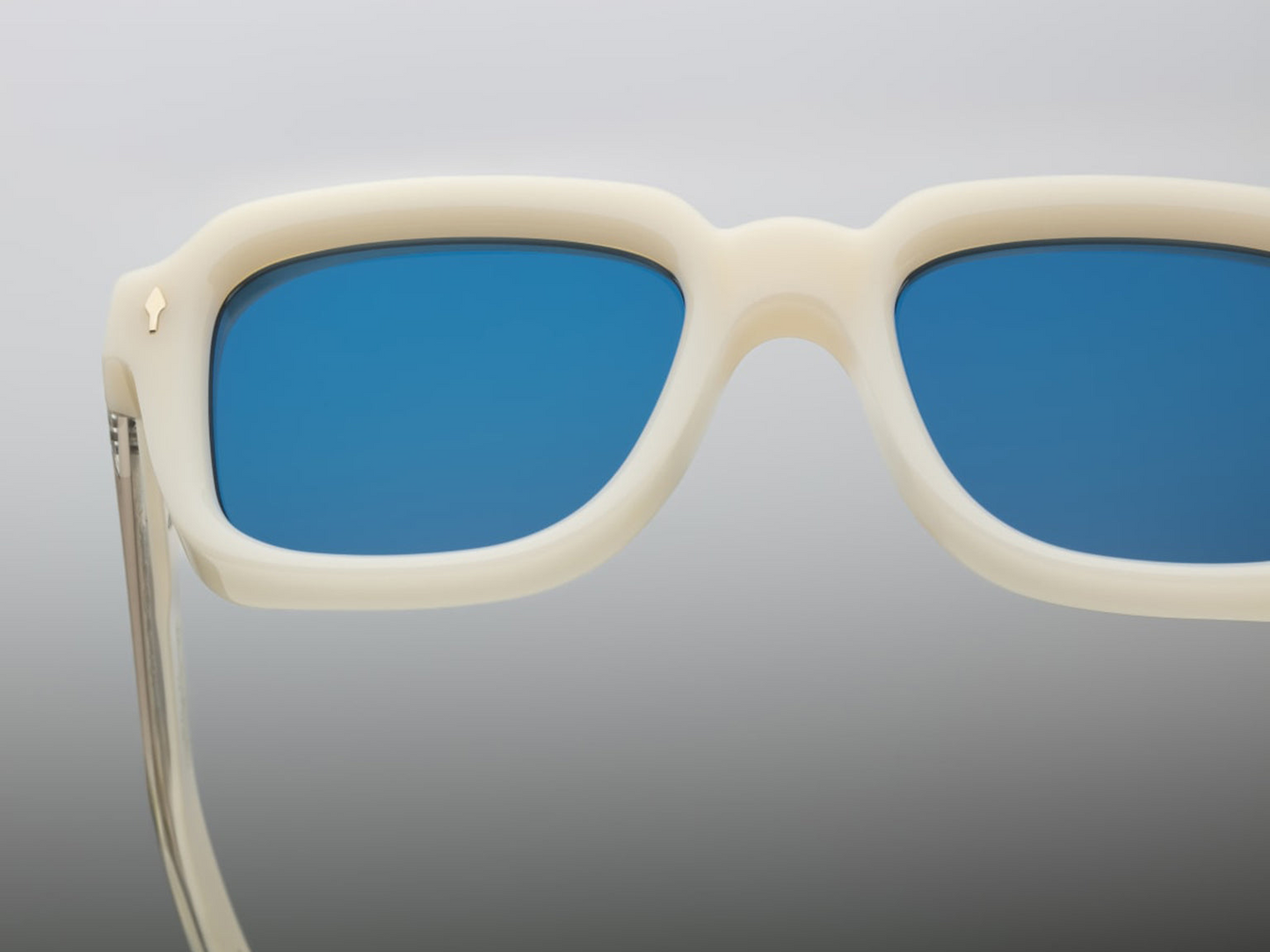 Jacques Marie Mage Taos in Mykonos sunglasses, bold, rectangular 10 mm white cured acetate frames evoking Mykonos’ architecture. They feature exposed silver wire‑core temples threaded with tribal-engraved detailing, vintage-style 4-base blue gradient CR39 lenses with backside anti‑reflective coating, and full UV protection. Inspired by Dennis Hopper’s eyewear in Easy Rider, this is a limited edition of 150 pieces at WINK Optometrists