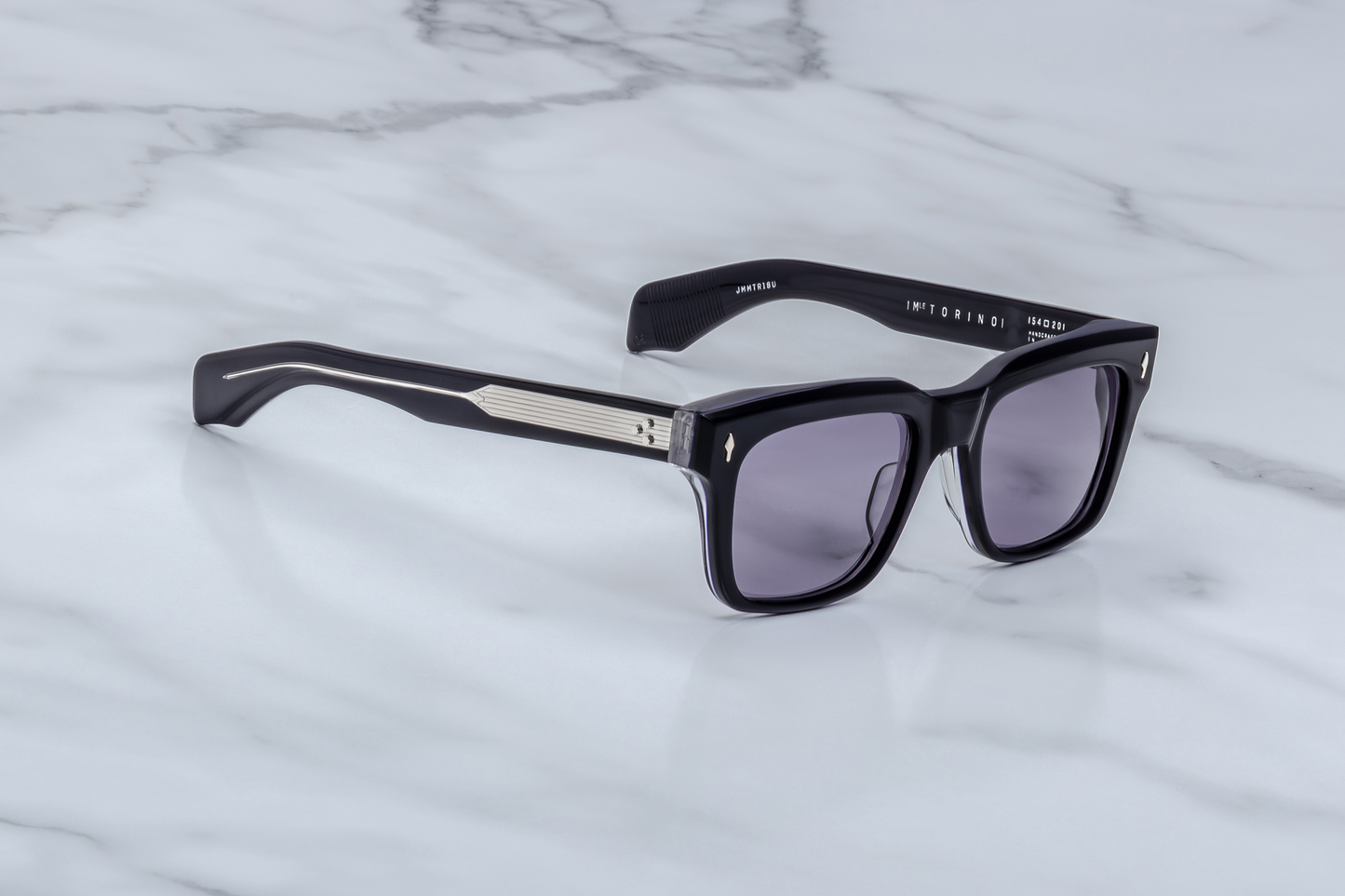 Angled side view of Jacques Marie Mage Fellini Hudson sunglasses showing thick blue acetate frame, purple lenses, and sculptural double-laminated temples.
