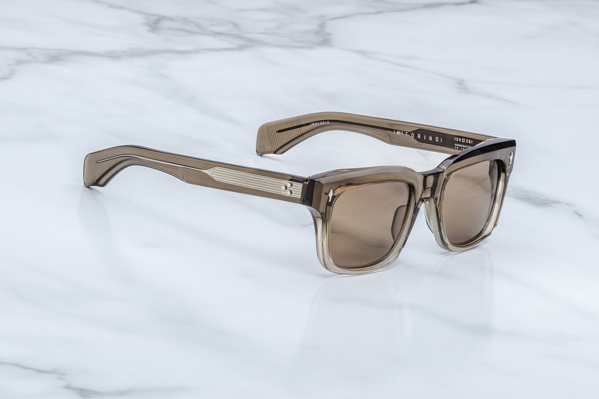 Three-quarter view of the Jacques Marie Mage Torino Lescot sunglasses. This angle highlights the frame's distinct architectural brow line beveling and the thick temples that expose a silver filigree wire core through clear laminated outer acetate.
