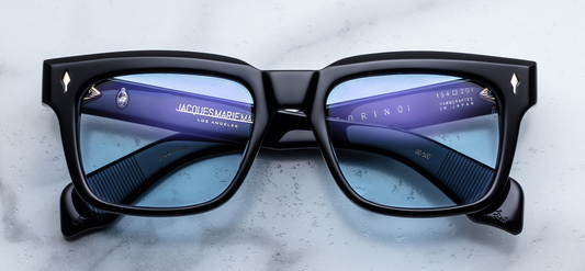Front view of Jacques Marie Mage Torino Obscure sunglasses. Displays a bold, 1960s-inspired rectangular 10mm block acetate frame in solid polished black, fitted with striking blue gradient lenses and dark gold arrowhead front pins. Wink Optometrists