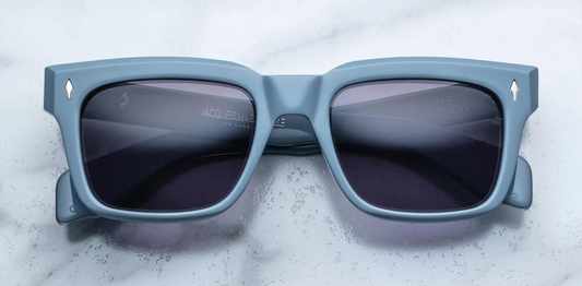Jacques Marie Mage Molino Tiger sunglasses — thick rectangular blue acetate frame with silver arrowhead pin, exposed silver wirecore, and stone-grey lenses