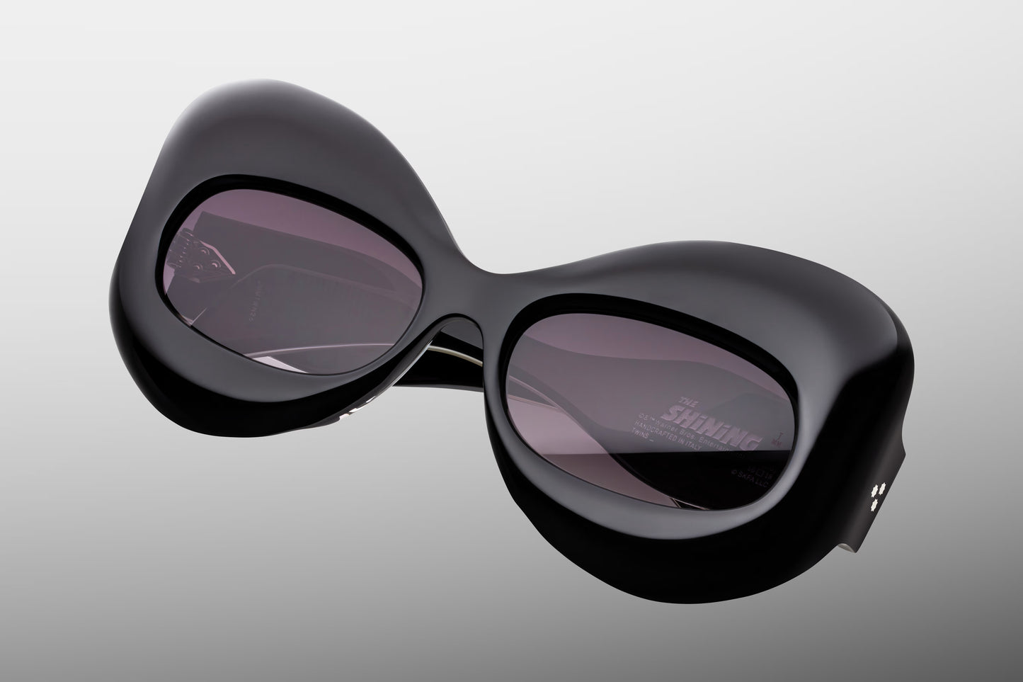 Close-up front detail of Jacques Marie Mage Twins Shadow frame showing butterfly lens shape, polished black acetate and silver rivets
Macro front view of JMM Twins Shadow sunglasses highlighting jet gradient lenses and cinematic frame design