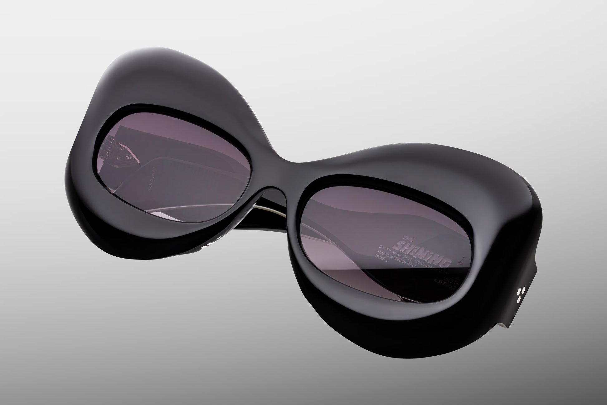 Close-up front detail of Jacques Marie Mage Twins Shadow frame showing butterfly lens shape, polished black acetate and silver rivets
Macro front view of JMM Twins Shadow sunglasses highlighting jet gradient lenses and cinematic frame design