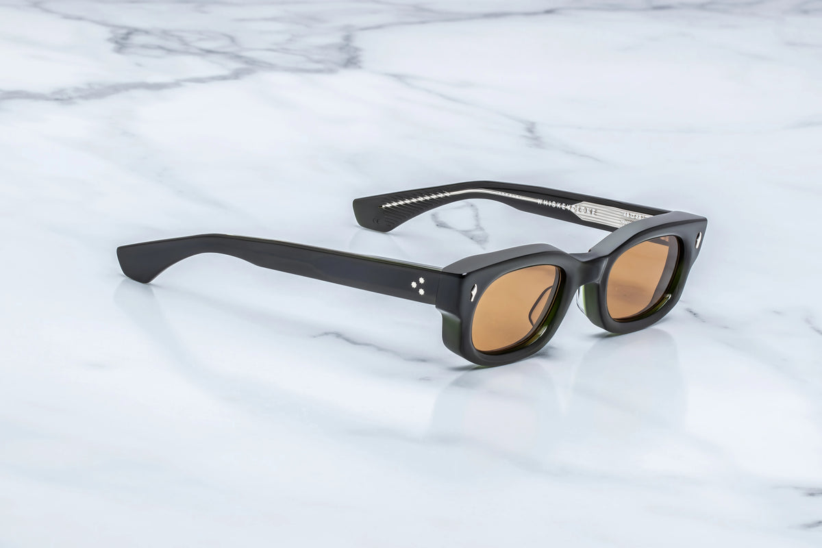Side profile view of the Jacques Marie Mage Whiskeyclone Bornéo sunglasses. The thick, sculpted double-laminated green acetate temple arms run straight back, tapering down toward the tips. The highly polished, glossy finish catches the light, revealing a subtle shift in the green hue through the translucent material.
