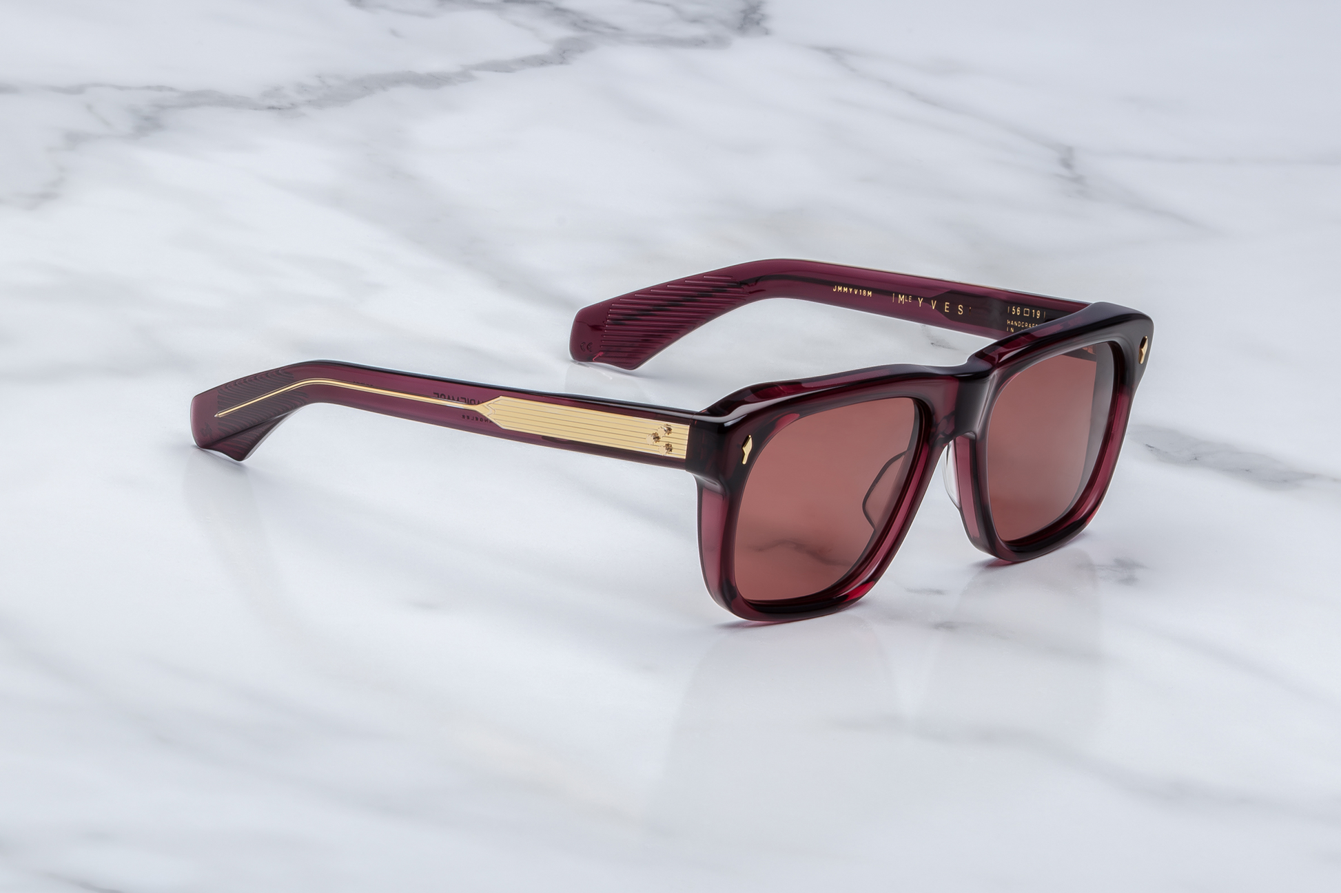 Side profile of Yves Amarena — double-laminated red acetate temples with dark gold arrowhead front pin and exposed gold wire-core running through the temple