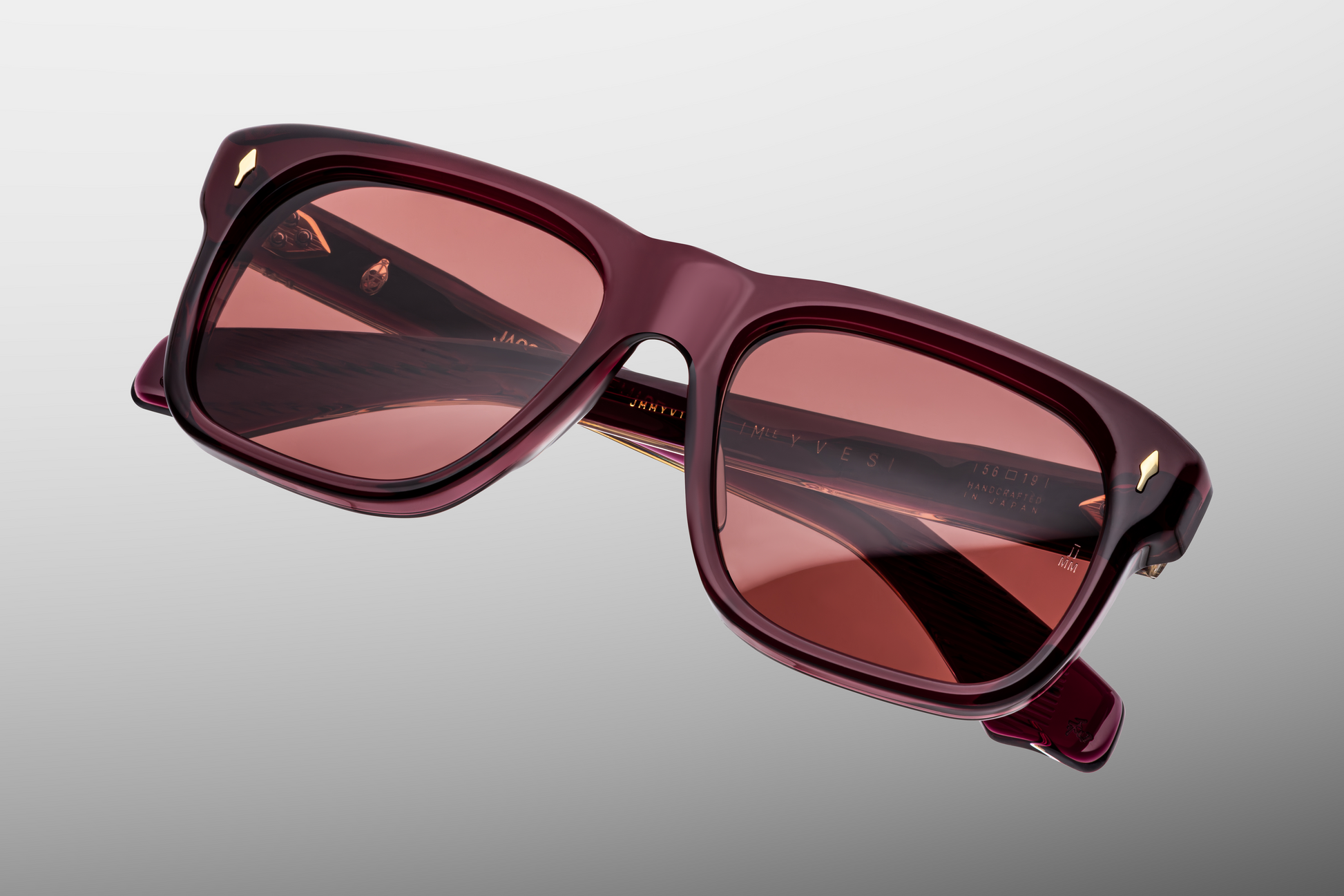 Back / inside of the Yves Amarena — deep red acetate frame showing the inner surface of the temples, with exposed dark-gold wire-core, engraved custom 7-barrel hinges, and lightly polished finish on the temple tips