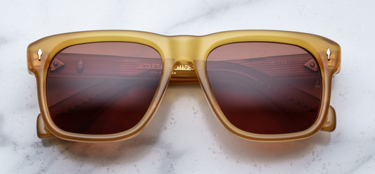 Front-facing view of Jacques Marie Mage Yves Honey sunglasses: a honey‑colored translucent acetate full‑rim rectangular frame with cinnamon‑brown lenses, featuring subtle rounded corners and slender light‑gold arrowhead pins at the upper corners.