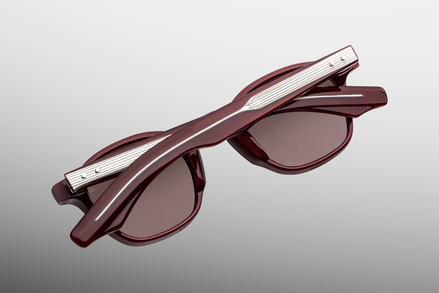 Rear perspective of the JMM Zephirin Bordeaux Empire temples, detailing the curved ear bends where the translucent deep burgundy-red acetate surrounds the internal gold-plated wirecore tips.
