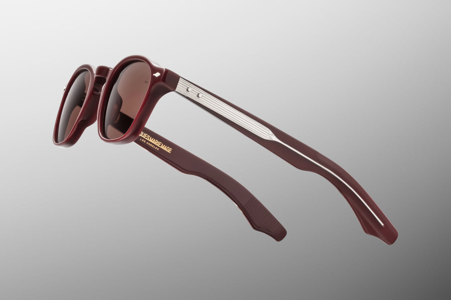 Side view of the JMM Zephirin Bordeaux Empire sunglasses temple arm, showcasing the glossy burgundy-red double-laminated acetate construction and the signature flush gold spur-shaped rivets.