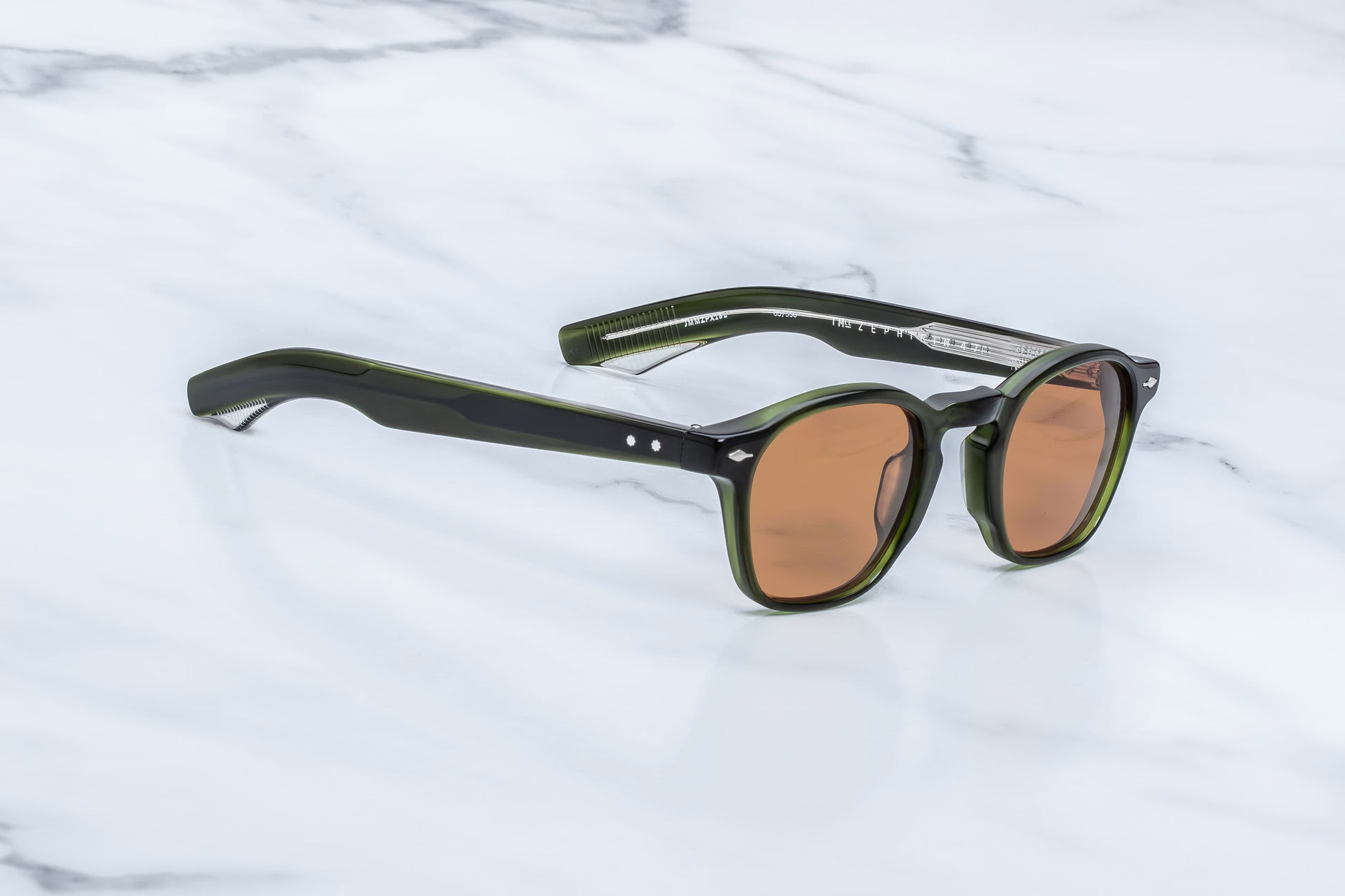 Three-quarter angled studio shot of the JMM Zephirin Borneo sunglasses, highlighting the retro keyhole bridge, distinct sculptural 10mm frame bevels, and rich forest-green acetate tones.