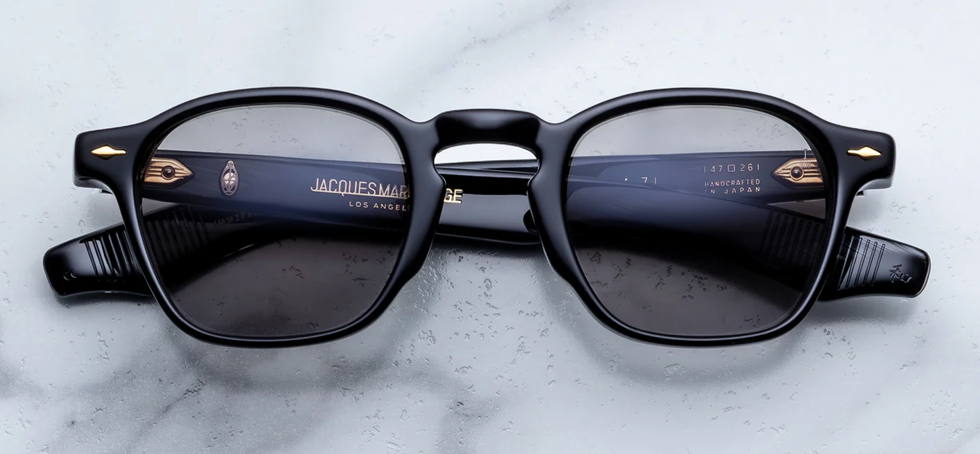 Front studio shot of Jacques Marie Mage Zephirin sunglasses in Griffin, showing a square 1940s-style frame in polished black acetate with Ash grey lenses and signature gold arrowhead front pins.