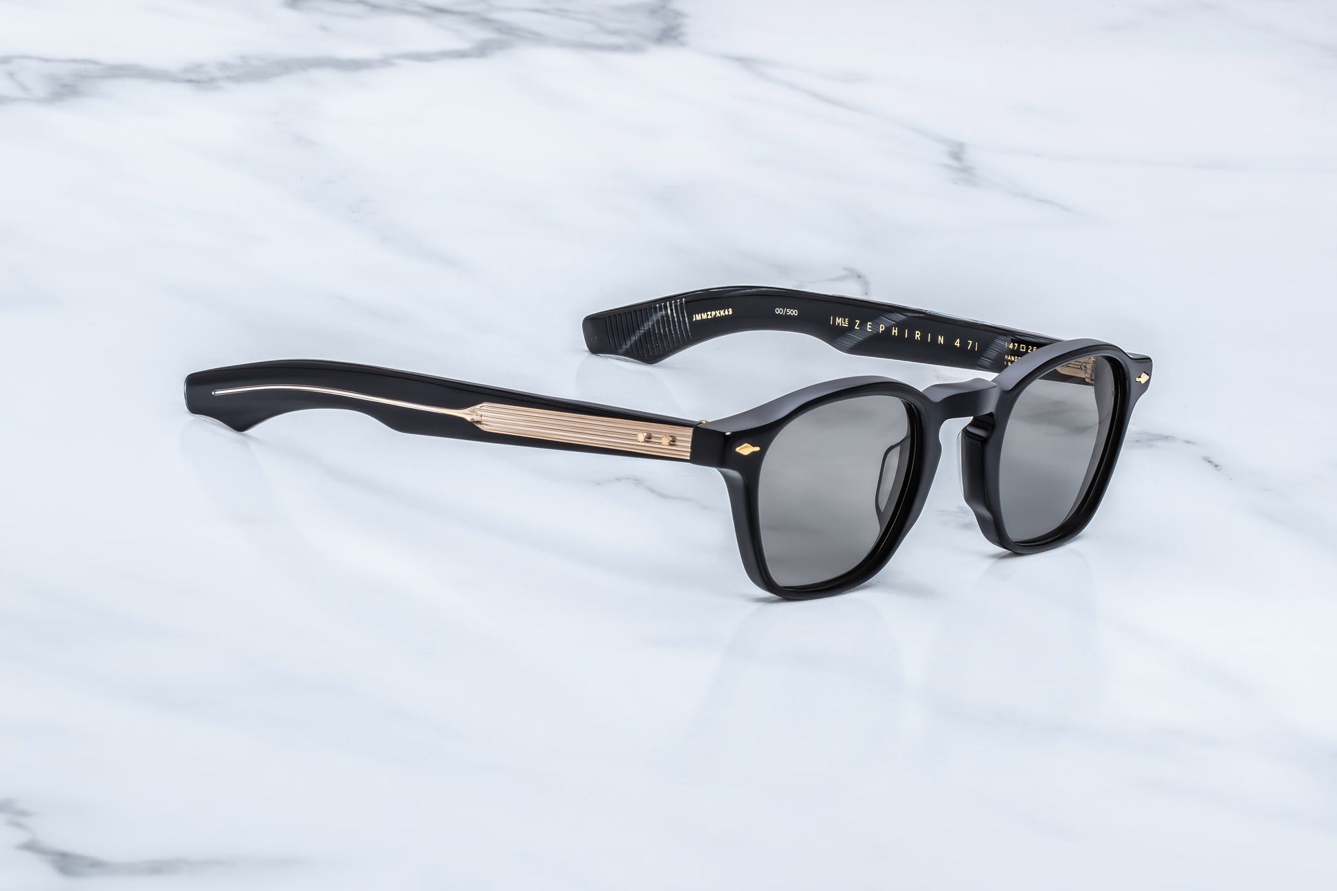 Three-quarter angled studio shot of the JMM Zephirin Griffin sunglasses, highlighting the structural beveling of the thick 10mm black block frame and its classic retro keyhole bridge.