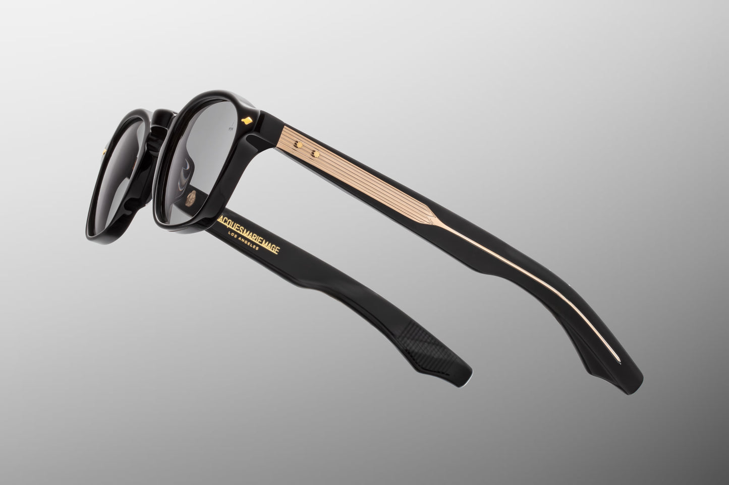 Side view of the JMM Zephirin Griffin sunglasses temple arm, showcasing the glossy black outer temple structure, gold spur-shaped rivets, and a glimpse of the custom inner metal core.