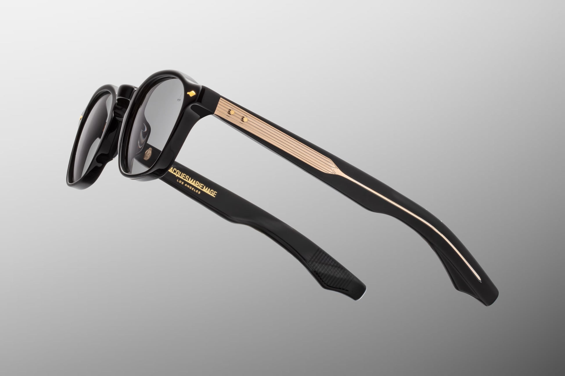 Side view of the JMM Zephirin Griffin sunglasses temple arm, showcasing the glossy black outer temple structure, gold spur-shaped rivets, and a glimpse of the custom inner metal core.