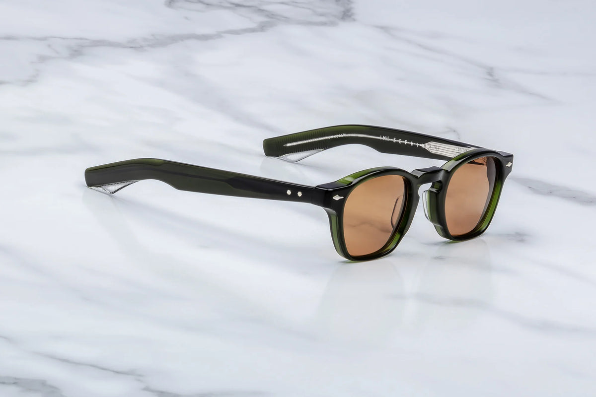 Three-quarter angle of the JMM Zephirin 47 Borneo, highlighting the robust green acetate brow line, the beveling around the orange lenses, and the front-facing silver arrowhead pin detail.