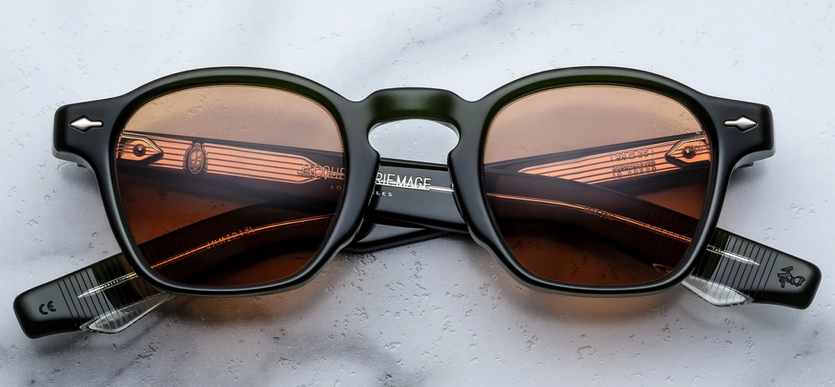 Front view of Jacques Marie Mage Zephirin 47 sunglasses in Borneo, showcasing a thick, polished green 10mm cellulose acetate rectangular frame, bold solid orange lenses, and signature silver arrowhead front pins at the outer corners