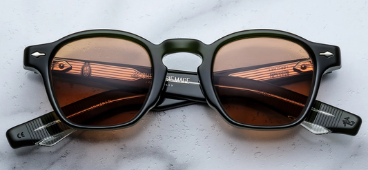 Front view of Jacques Marie Mage Zephirin 47 sunglasses in Borneo, showcasing a thick, polished green 10mm cellulose acetate rectangular frame, bold solid orange lenses, and signature silver arrowhead front pins at the outer corners
