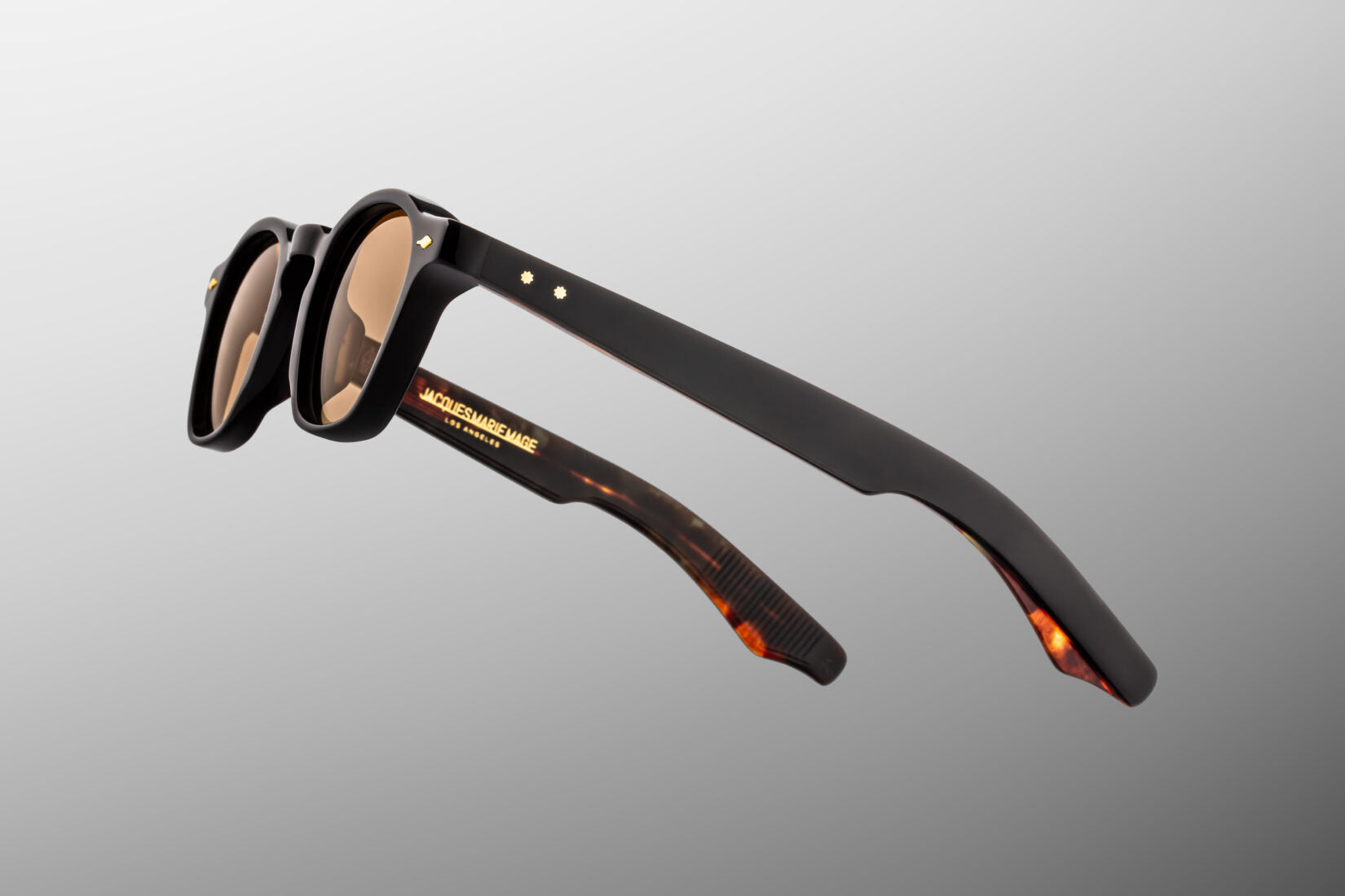 Close-up of Jacques Marie Mage Zephirin Noir 15 temple featuring dark gold arrowhead pins, exposed engraved gold wirecore and handcrafted Japanese acetate construction