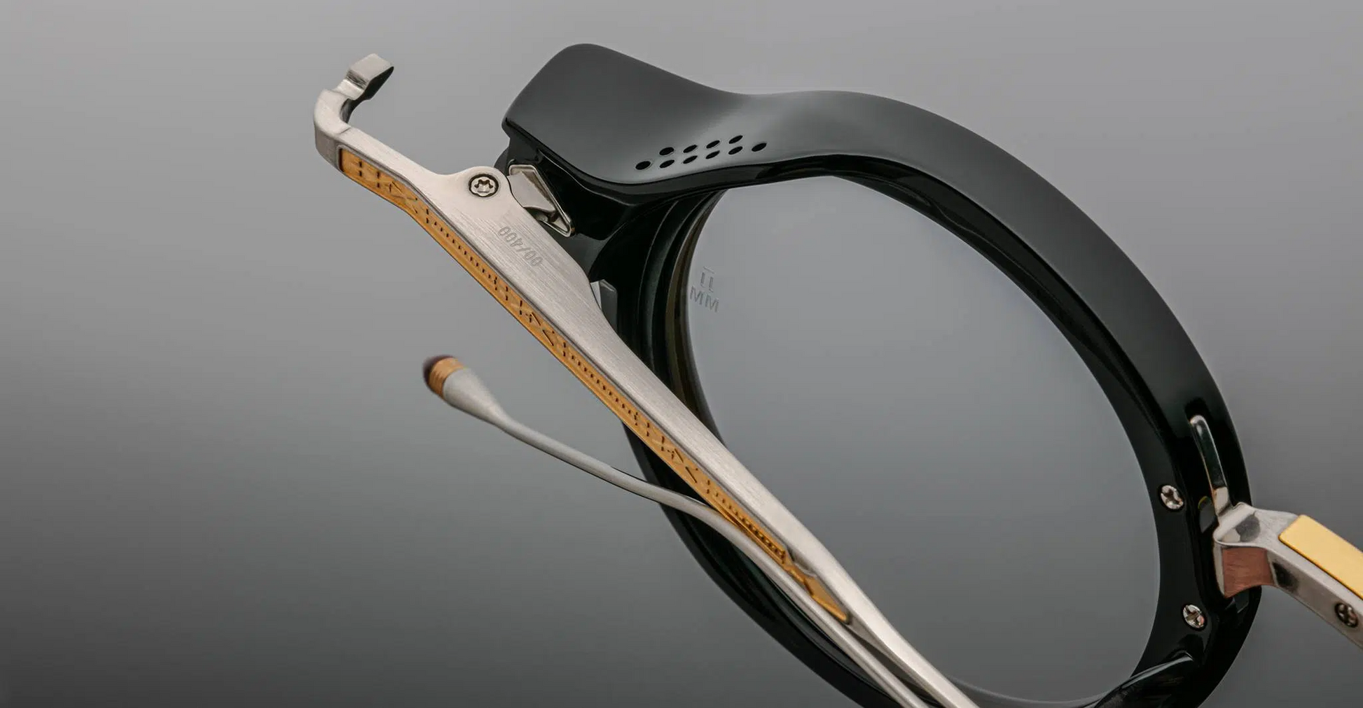 Close-up side detail of Jacques Marie Mage Norman optical frames in noir, showing the polished acetate rim, brushed metal temple with exposed core, hinge hardware, and adjustable nose pad.