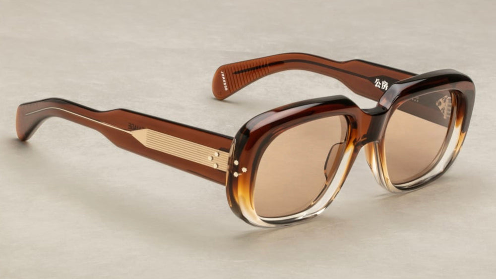 Discover the Jacques Marie Mage Kobo sunglasses in Hickory Fade—a limited edition frame with only 350 pieces produced. Crafted in Japan, these sunglasses feature a 10mm brown cured cellulose acetate frame and custom double-laminated acetate temples with exposed silver wirecore. The design includes a silver signature arrowhead front pin and silver domed 3D metal cameo logo. Equipped with tan CR39 lenses offering 100% UV protection and a backside anti-reflective treatment, available at WINK Optometrists