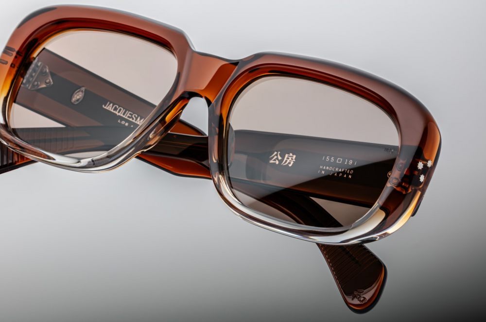 Jacques Marie Mage Kobo sunglasses in Hickory Fade—limited edition eyewear featuring a 10mm brown cured cellulose acetate frame, custom double-laminated acetate temples with exposed silver wirecore, and silver signature arrowhead front pin. Handcrafted in Japan with 100% UV protection and tan CR39 lenses. Ideal for larger faces, embodying bold design and artisanal craftsmanship. Available at WINK Optometrists