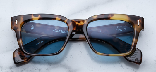 Front view of Jacques Marie Mage Molino sunglasses in Havana 8, featuring a bold 10mm double-laminated cured cellulose acetate frame with a rich amber-to-translucent beige gradient. The design includes subtle bevel detailing, silver arrowhead front pins, exposed silver wirecore with custom hairline engraving, and silver tension-secured custom 7-barrel hinges with spur-shaped rivets. The azure blue CR39 lenses offer 100% UV protection and backside anti-reflective coating. Handcrafted in Japan, this limited-e