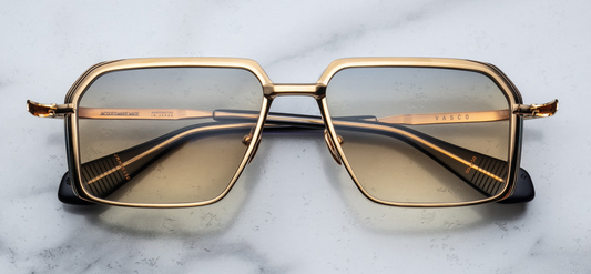 Front view of Jacques Marie Mage Vasco Bay sunglasses, showcasing a sharp rectangular silhouette with a V-shaped profile. The frame is crafted from gold-toned beta titanium, featuring sculpted volume cuts and hairline epoxy detailing. Acetate temple tips with exposed wirecore details complement the design. The yellow gradient CR39 lenses offer 100% UV protection and backside anti-reflective treatment.