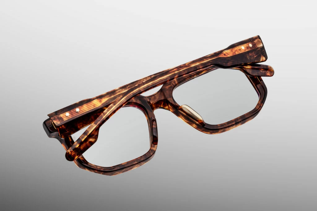 Close-up interior detail shot of the Jacques Marie Mage Argyle frame architecture. The inner view highlights the warm mottled tortoiseshell acetate against the premium dark gold metallic hardware components. Distinctive text foil-stamped in gold on the inner temple arm indicates its exclusive limited-edition batch number and the official "Handcrafted in Japan" production text. Available at WINK Optometrists.
