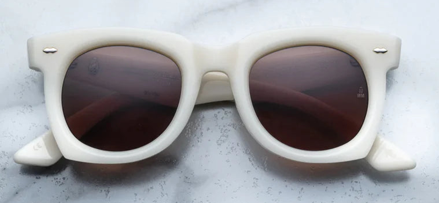 The ‘Ava’ is a sleek '50s inspired glasses with graceful lines, signature double-arrowhead front pins, and custom double-laminated temples with refined 'Lever' wire core. White 8mm cured cellulose acetate frame with custom double laminated acetate temples featuring precious metal hardware and primary brown lenses. Limited edition of 150 pieces. Handcrafted in Japan. Size 45/24. 