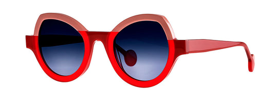 Theo Modernisme eyewear in red and pink, featuring a unique geometric design with bold, angular frames and contrasting color accents, set against a neutral background.